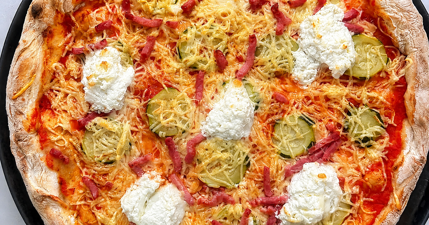 Pizza maison à la pulpe de tomates, aux courgettes, à la burrata, à l’emmental et aux lardons, recette d’été dans le Var
